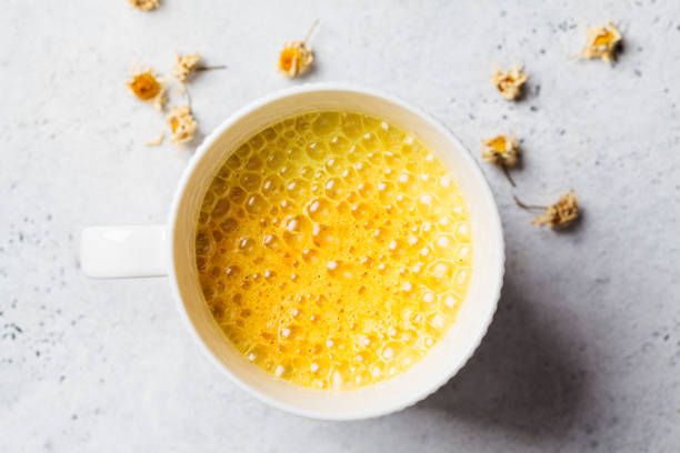Golden turmeric chamomile moon milk in white cup. Ayurveda drink, healthy lifestyle, remedy for insomnia. stock photo