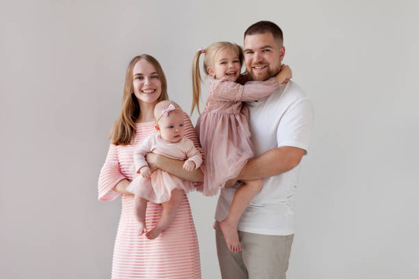 familia feliz con dos hijos sobre fondo blanco aislado. padres sonrientes con niños niñas en sus brazos con elegantes ropas festivas - family with two children father clothing smiling fotografías e imágenes de stock