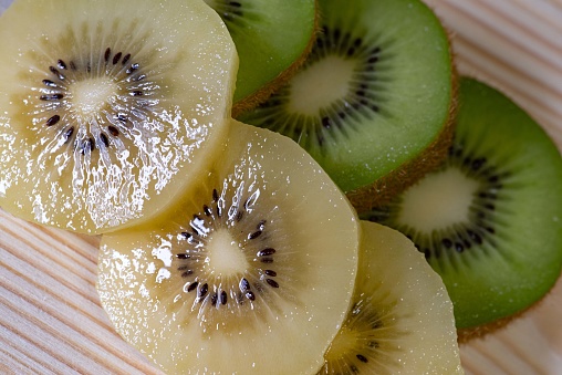 Green and yellow kiwi fruits on a plate top view