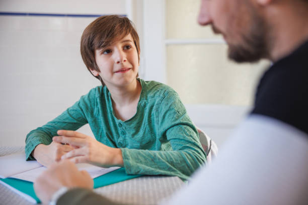 istock Boy doing homework at the table and listening to his father 1425487794
