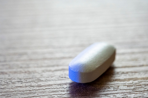 A white colored vitamin capsule taken daily to support metabolism and health.