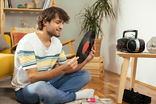 Young man enjoying at home, playing his old cd's and records and enjoying music from the retro cd player