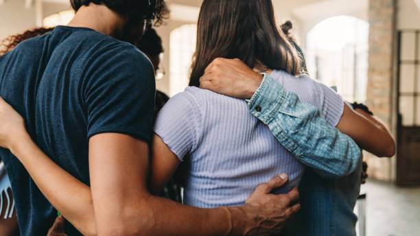 les gens s’embrassent ensemble dans leur bureau - embracing photos et images de collection