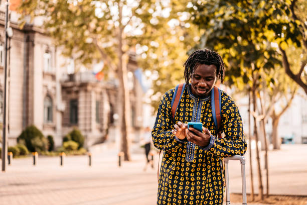 turista africano perdido usando mapa en un teléfono inteligente - tourist map men holding fotografías e imágenes de stock