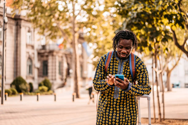 turista africano perso utilizzando la mappa su uno smartphone - tourist map men holding foto e immagini stock