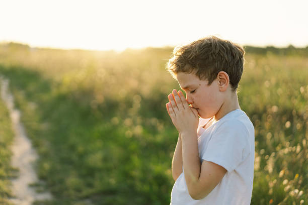 istock Boy closed her eyes and praying in a field at sunset. 1425501446