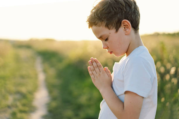 istock Boy closed her eyes and praying in a field at sunset. 1425501498