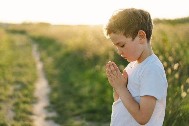 istock Boy closed her eyes and praying in a field at sunset. 1425501499
