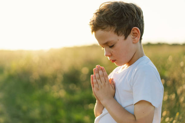 istock Boy closed her eyes and praying in a field at sunset. 1425501500