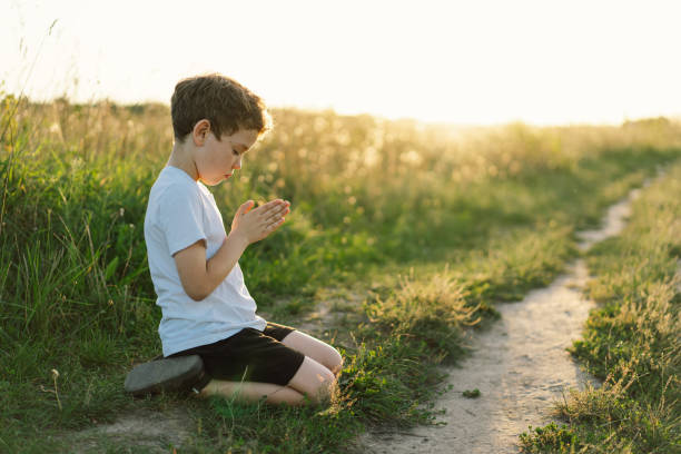 istock Boy closed her eyes and praying in a field at sunset. 1425501650