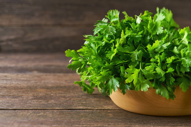 istock fresh parsley in a wooden bowl on the table, copy space for text. 1425501751