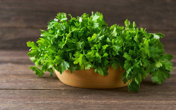 istock fresh parsley in a wooden bowl on the table, selective focus, rustic style. 1425501752