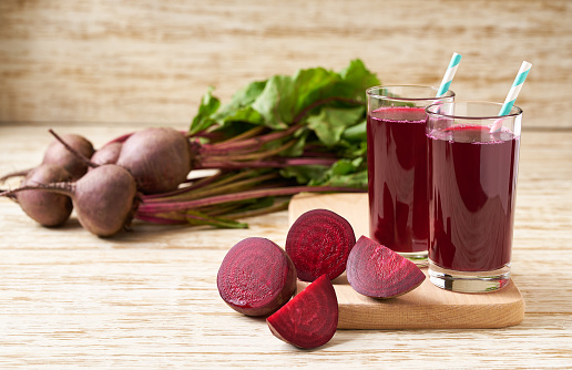Fresh beet juice in glasses on a  white wooden table, selective focus.