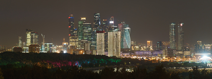 Long exposure photography of Moscow cityscape during autumn night. Blurred lights of the city. Bright lighting of Moskva river embankment. Skyscrapers of Moscow business district. Panoramic image.