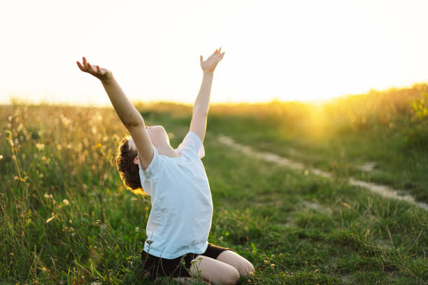 istock Boy closed her eyes and praying in a field at sunset. 1425510946