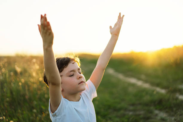 istock Boy closed her eyes and praying in a field at sunset. 1425510973