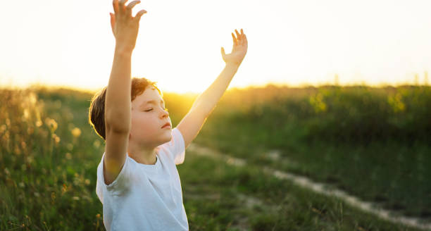 istock Boy closed her eyes and praying in a field at sunset. 1425510976