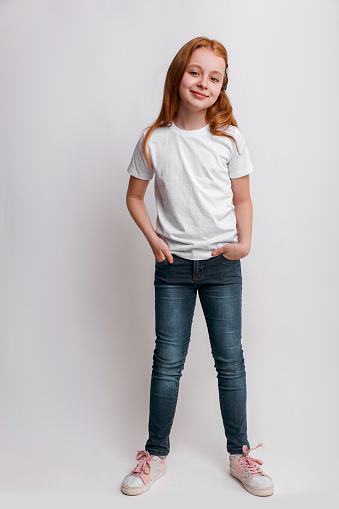 Kid in white t-shirt and jeans in studio. Full length portrait little girl