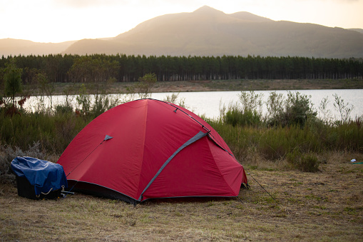 A red tent set up to camp on the banks of Gubu Dam in Stutterheim, South Africa