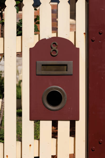 Cream colored metal mailbox on a fence.