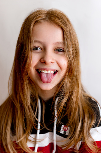 Portrait of funny teenager child girl smiling and showing tongue in camera. Close-up