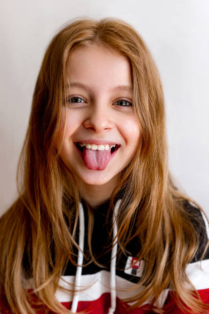 Portrait of funny teenager child girl smiling and showing tongue in camera. Close-up kid portrait stock photo