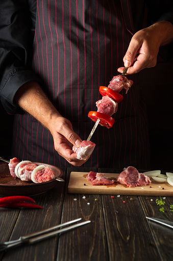 The process of cooking shish kebab from raw lamb meat in the kitchen with the hands of a chef. Asian traditional cuisine