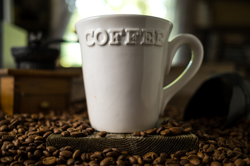 White Mug with the Word Coffee on it in a Pile of Coffee Beans
