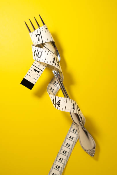 istock Silver Fork with Measuring Tape Wrapped Aroung It on a Yellow Background 1425519129