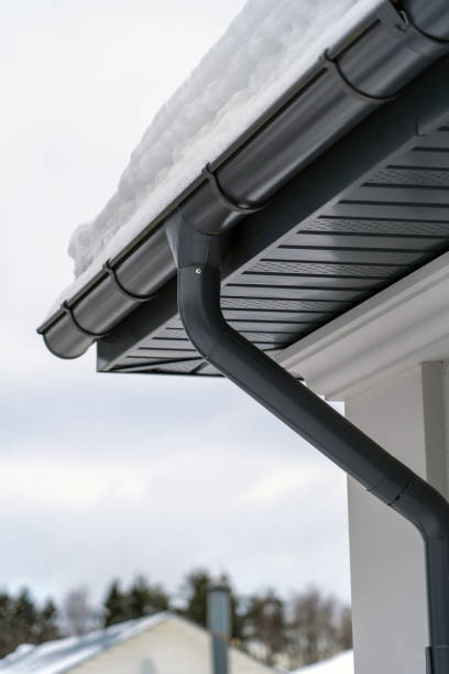 istock Metal Downpipe system, Guttering System, External downpipes and drainage pipes under snow. Corner of house with roof made of gray metal tiles and gutter covered with thick layer of snow in winter. 1425519172