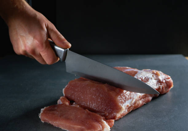 istock The chef is cutting fresh raw meat into steaks. Close-up on a gray background. 1425519242