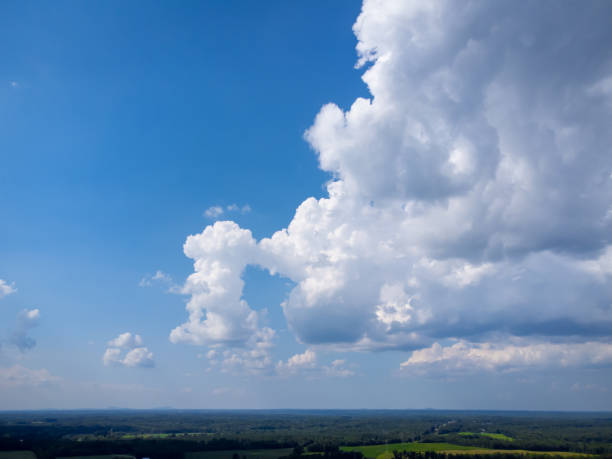 istock Towering cumulonimbus clouds over green rural landscape with deep blue sky and negative space for copy. 1425527695