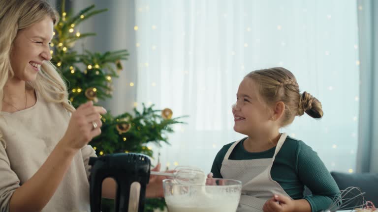 Caucasian mother and daughter preparing sweet food in the kitchen before Christmas. Shot with RED helium camera in 8K.