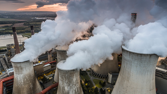 Aerial view of air pollution by carbon dioxide and steam coming out of large power station cooling towers.