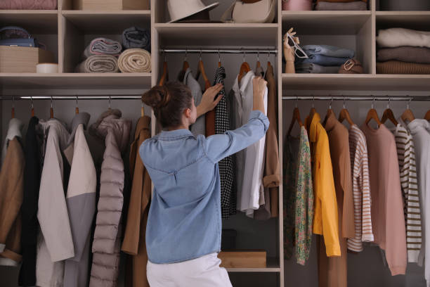 mujer joven eligiendo ropa en armario armario, vista trasera - vestuario fotografías e imágenes de stock