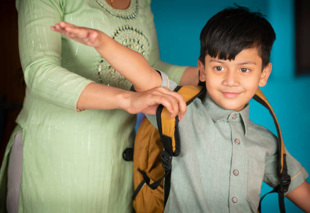 istock Indian mother getting her son ready for school and adjusting his backpack. 1425540982