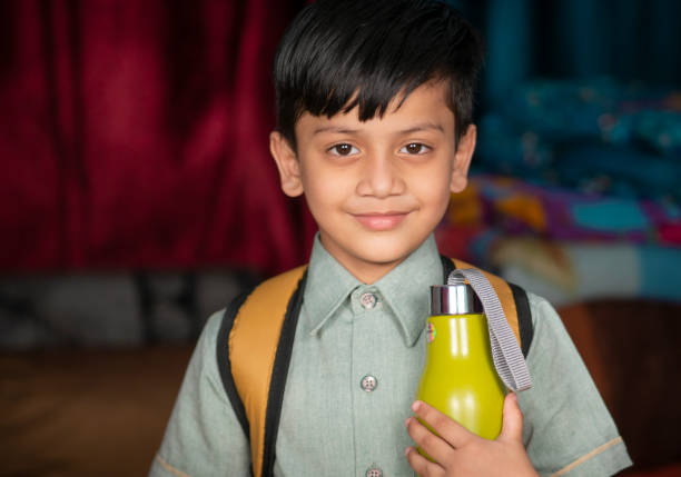 retrato de um garoto da escola com uma mochila segurando uma garrafa de água na mão. - water child bottle little boys - fotografias e filmes do acervo