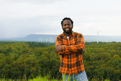 Portrait of man smiling to camera at rural outdoor with wind turbine as background.