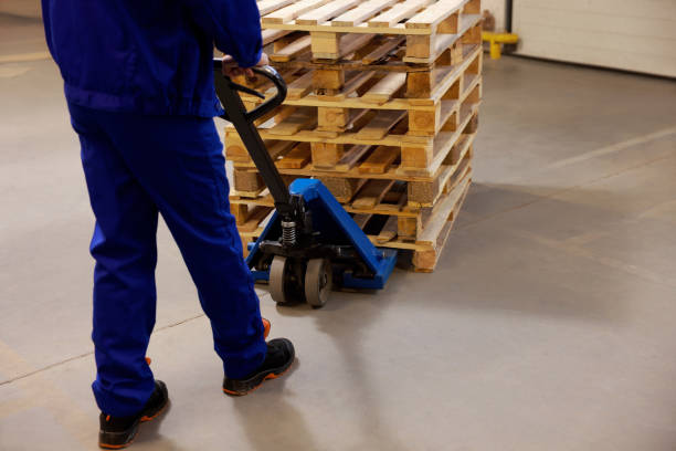 istock Worker moving wooden pallets with manual forklift in warehouse, closeup 1425543913