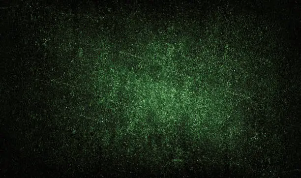 Photo of Black dark green grunge background with light spot, particles. Old rough dirty scratched painted wall surface.