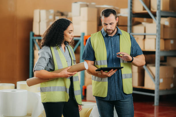 Logistics, supply chain and shipping factory employees with tablet in hand, smile in shipping or cargo factory warehouse. Management, boss or CEO working distribution industry and delivery company stock photo