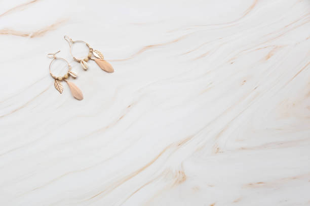 istock A pair of earrings on a marble background with copy space. 1425550072