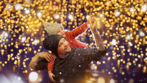 padre e hija decoran afuera para navidad. fiesta familiar. - holiday fotografías e imágenes de stock