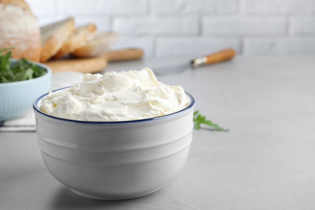 istock Bowl of tasty cream cheese on grey table. Space for text 1425556693