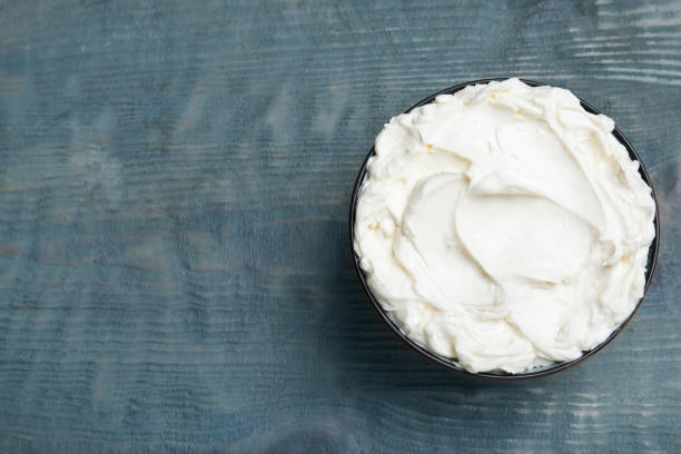 istock Tasty cream cheese on light blue wooden table, top view. Space for text 1425556736
