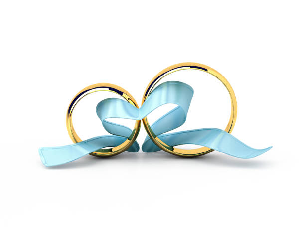 Wedding rings with a blue ribbon in a heart shape isolated on white. stock photo