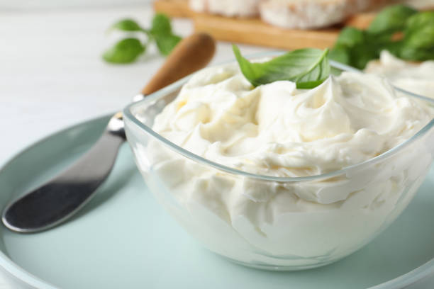 istock Tasty cream cheese with basil and knife on white table, closeup 1425557755