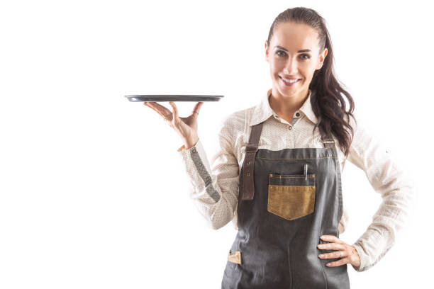 Waitress holding a tray in her hand is dressed in apron posing on an isolated background.
