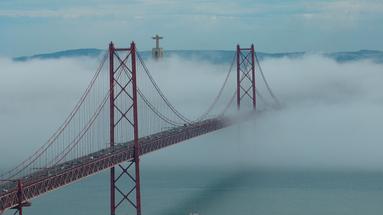 The main bridge of the capital of Portugal, 25 de Abril bridge, in Lisbon that unites the two banks through which so many people
 pass by, car or train, under a  incredible moment about the influence of a natural phenomenon