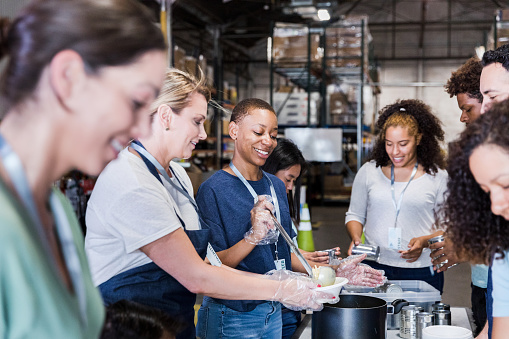 The diverse group of volunteers work together at the warehouse to help serve food.